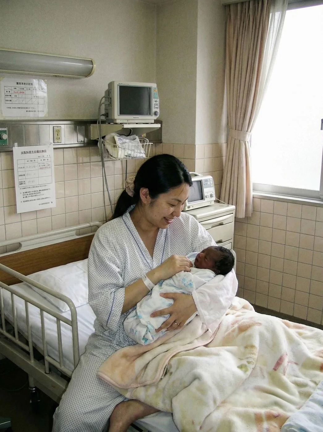 Eva as a newborn, held by her mother in a hospital room in Japan